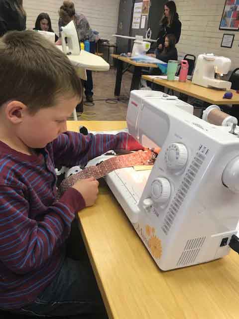 Young boy sewing at quilt camp